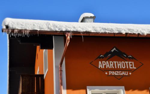 a snow covered roof of a building with a sign on it at Aparthotel Pinzgau in Neukirchen am Großvenediger