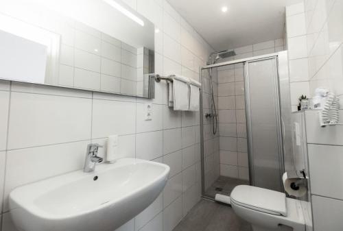 La salle de bains blanche est pourvue d'un lavabo et d'une douche. dans l'établissement Hotel & Restaurant Tanne, à Fischingen