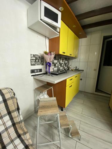 a small kitchen with yellow cabinets and a microwave at House&House 84 in Petropavlovskaya Borshchagovka