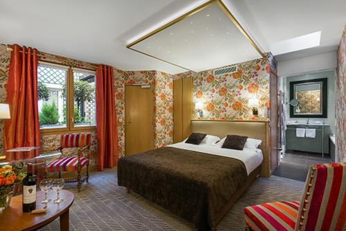 パリにあるホテル サンポール リヴ ゴーシュのベッド、テーブル、椅子が備わるホテルルームです。
