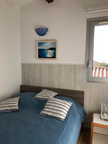 appartement vue mer في كاب داغد: غرفة نوم بسرير ازرق ونافذة
