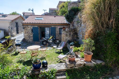 einen Garten mit Tisch und Stühlen und ein Haus in der Unterkunft Petit gite du Bistrot d ici in Saint-Saturnin