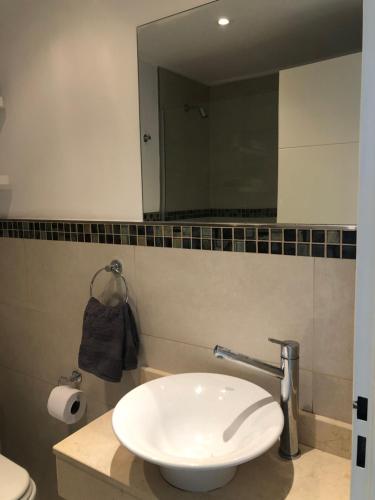 a bathroom with a white sink and a mirror at Administración MAIPU 1D DEPTO PREMIUM in Tandil