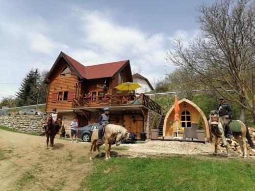 a group of people riding horses in front of a wooden house at Vila Jelena - BUNGALOV in Crni Vrh