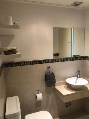 a bathroom with a sink and a toilet and a mirror at Administración MAIPU 1D DEPTO PREMIUM in Tandil