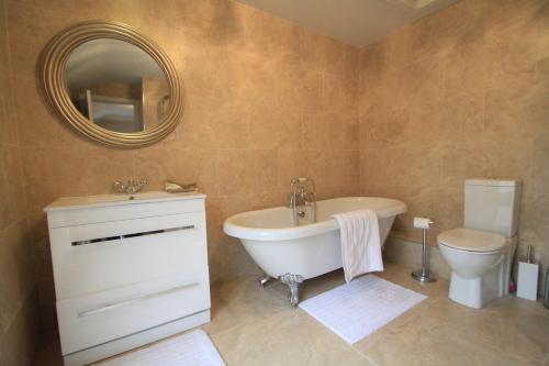 a bathroom with a tub and a toilet and a mirror at Willoughby Place in Enniskillen