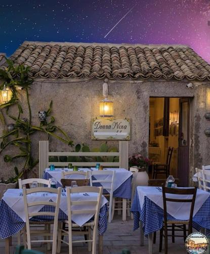 a restaurant with white tables and chairs at night at Mediterraneo Apartments ORO in Marzamemi