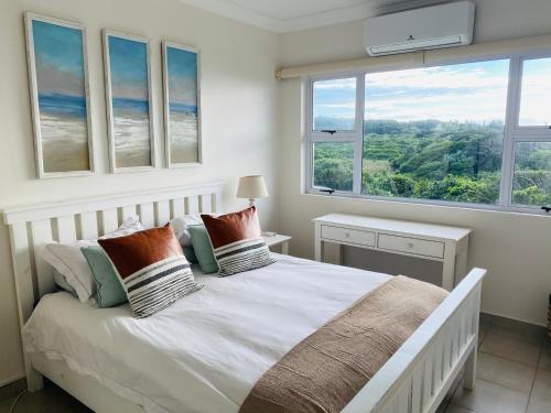 a bedroom with a large white bed with windows at Unit 4 Umzimkulu - Mangroves beach estate in Melville