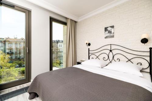 a bedroom with a large bed and large windows at Native Apartments Sukiennicza 8 in Krakow