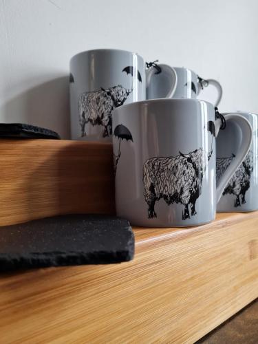 a group of three coffee mugs with sheep and an umbrella at No.8 in Stornoway