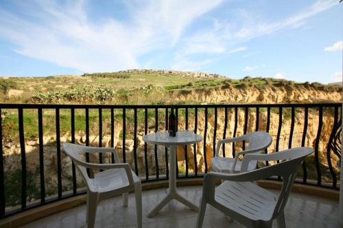 two chairs and a table on a balcony with a view at Spacious apartment in Marsalforn, Gozo in Marsalforn