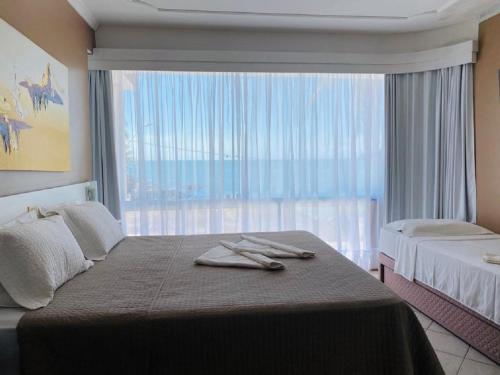 a bedroom with two beds and a large window at Pousada Castellammare in Bombinhas