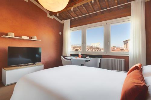 a bedroom with a bed and a tv and a table at 1881 LUXURY SUITES in Verona