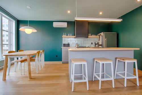 a kitchen with green walls and a table and stools at Les Lofts Dorchester - Par Les Lofts Vieux-Québec in Quebec City