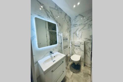 La salle de bains est pourvue d'un lavabo, de toilettes et d'un miroir. dans l'établissement Deauville Plage - Balcon, Vue Mer & Ville à pied, à Deauville