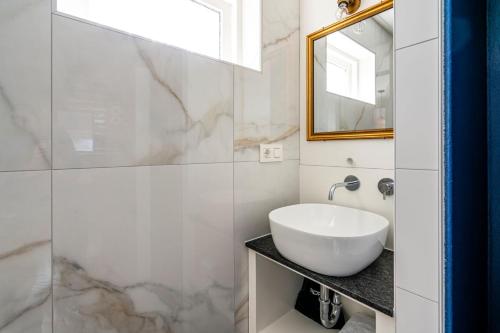 Un baño blanco con lavabo y espejo. en Charley's Home 2 personen, en Westkapelle