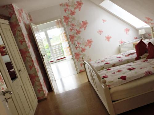 - une chambre avec un lit orné de fleurs sur le mur dans l'établissement Fewo Elbblick im Haus Lühegarten, à Grünendeich