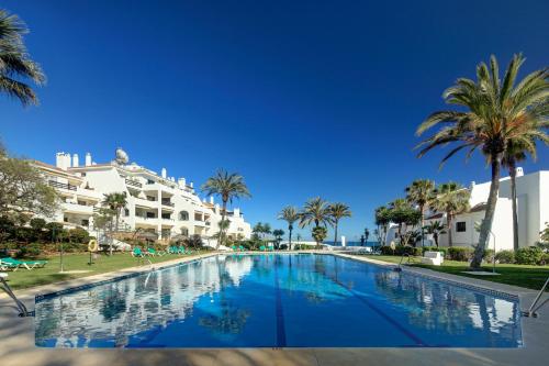 ein großer Pool mit Palmen und Gebäuden in der Unterkunft Coral Beach Aparthotel in Marbella