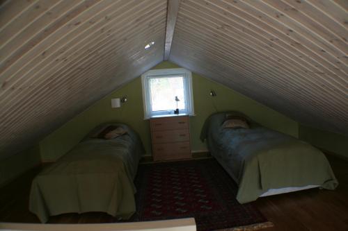 a attic room with two beds and a window at Sjöställe Gudö in Vendelsö