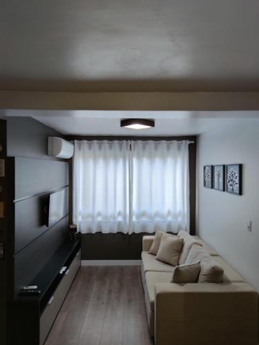 a living room with a couch and a window at Apartamento no Residencial Vert em Bento Gonçalves-RS in Bento Gonçalves