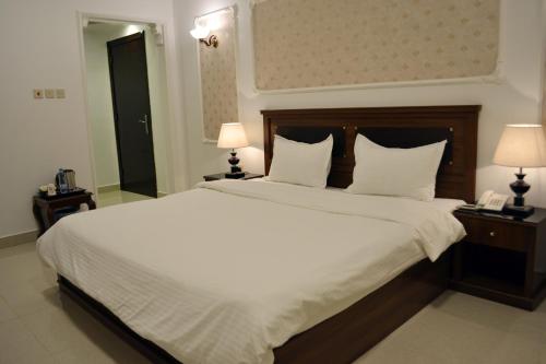 a bedroom with a large bed with white sheets and pillows at فندق جلنار الراقي للايواء السياحي in Al Madinah