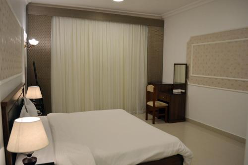 a bedroom with a white bed and a dresser in it at فندق جلنار الراقي للايواء السياحي in Al Madinah