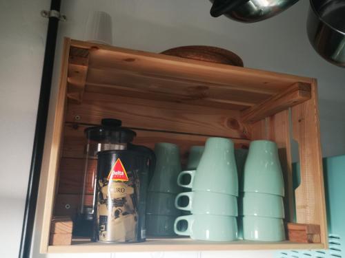 a cupboard filled with green cups and a bottle at Family Surf Home - Hostel in Mafra