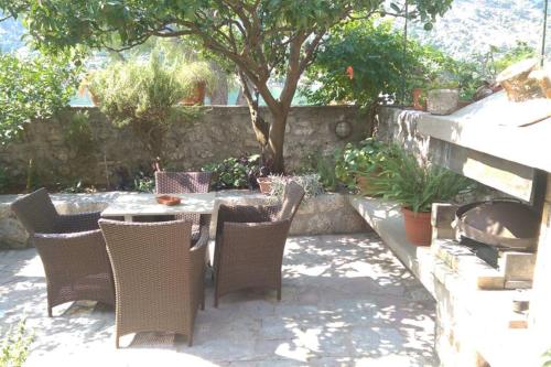 a patio with a table and chairs and a tree at Garden Apartment- near sea 2 in Dobrota