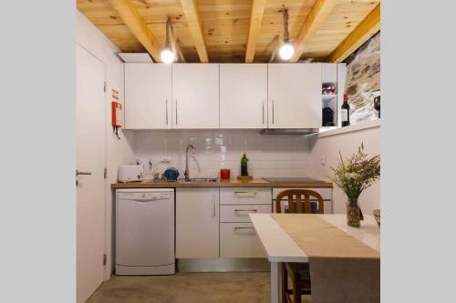 a kitchen with white cabinets and a table at Casa do Avô Alváro - Refugio do Rei in Casal do Rei