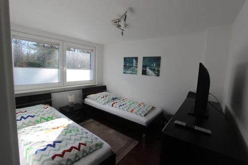 Zimmer mit 2 Betten, einem Schreibtisch und einem Fenster in der Unterkunft Samlandhaus in Timmendorfer Strand