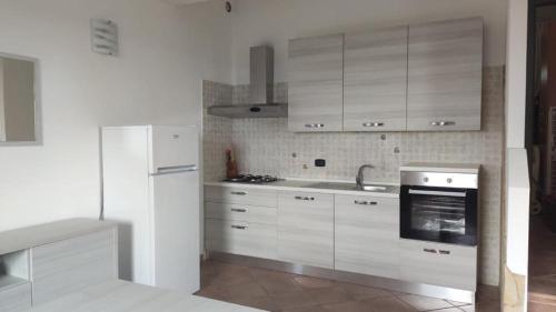 a kitchen with white cabinets and a white refrigerator at Villino Aurora in Villaputzu