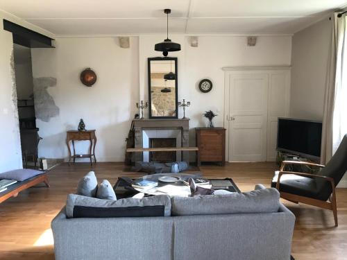 a living room with a couch and a tv at Golf Val de Sorne Vernantois Maison vigneronne in Vernantois