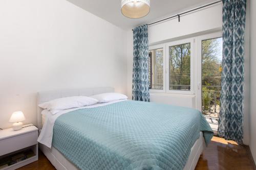 a bedroom with a bed with blue curtains and a window at Niklas Apartments in Vantačići