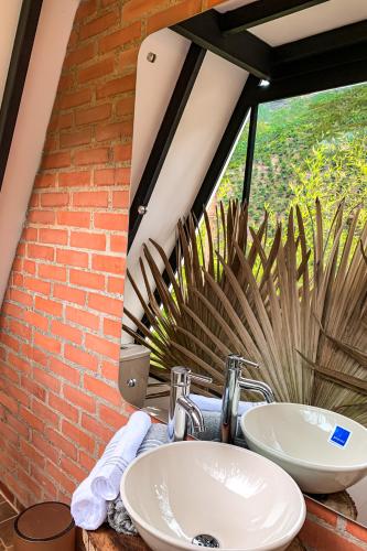 a bathroom with two sinks and a brick wall at Intrepido Glamping in Chinchiná