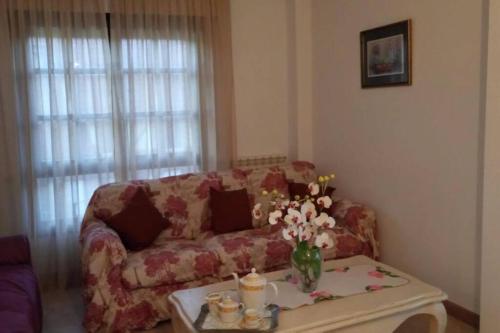 a living room with a couch and a table with flowers at CHALET CERCA DE NOJA CON ACCESO A SPA in Beranga