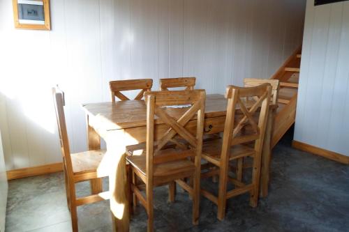 a wooden dining room table with four chairs at Apart Hotel Curahue in Junín de los Andes