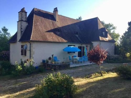 a white house with a blue umbrella in front of it at Location de vacance au coeur du Périgord Noir in Le Bugue