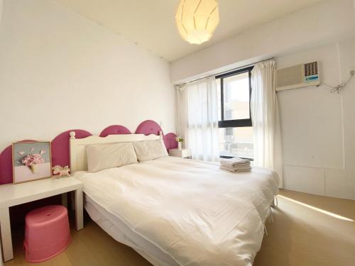 a bedroom with a large white bed with a pink headboard at Fengjia 101 in Taichung