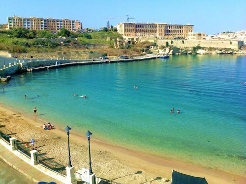 Un grupo de personas nadando en el agua en una playa. en Town House with Private Pool in Village Centre, en Kalkara