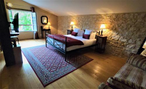 PineuilhにあるLA CARRETERIE - Maison de Famille{s}のベッドと石の壁のある寝室