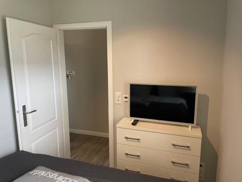 a bedroom with a flat screen tv on a dresser at Strandnest in Wyk auf Föhr