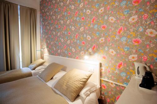 a bedroom with two beds and a floral wallpaper at Hotel Bencidormi in Florence