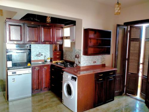 a kitchen with wooden cabinets and a washing machine at Lazorde bay Sidi Abd El Rahman لازوردى باى apartment in El Alamein