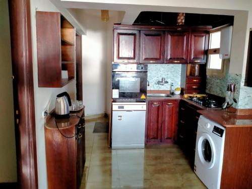 a kitchen with wooden cabinets and a white dishwasher at Lazorde bay Sidi Abd El Rahman لازوردى باى apartment in El Alamein