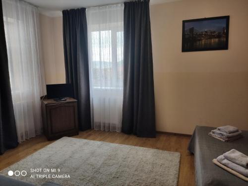a bedroom with a bed and a window with curtains at Apartments Domovik on Beregovskaya 3 in Mukacheve