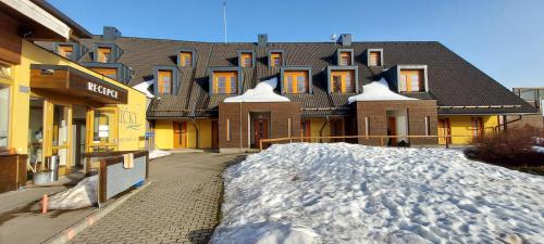 a building with a pile of snow in front of it at Wellness apartmány Říčky v Orlických horách in Říčky