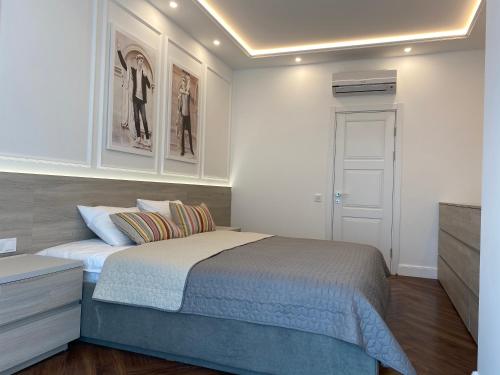 a bedroom with a bed and a white wall at Modern Classic 2 bedroom apartment near Most City in Dnipro