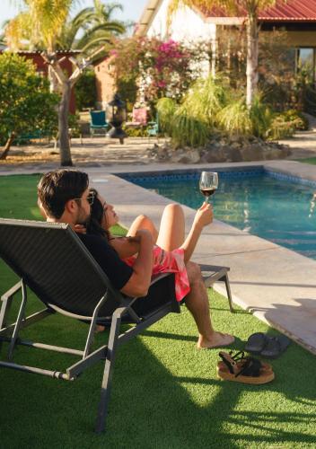 a man and woman sitting in a lawn chair with a glass of wine at Terra del Valle Bed & Breakfast in Valle de Guadalupe