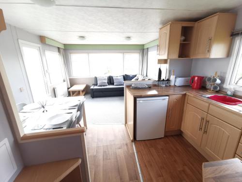 a kitchen and living room with a couch in the background at No99 Static Caravan Widemouth Fields 3 mins from beach in Poundstock