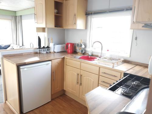 a kitchen with wooden cabinets and a stove top oven at No99 Static Caravan Widemouth Fields 3 mins from beach in Poundstock